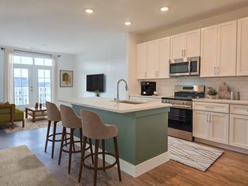 A kitchen with a green island and white cabinets.